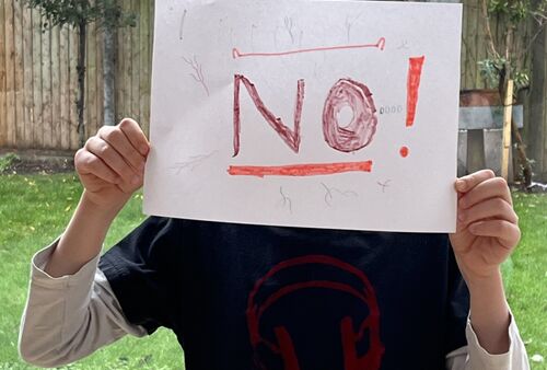 Eine Person zeigt ein Blatt Papier mit dem Wort NO!