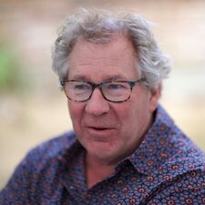 A portrait of Richard Cockett: a man with gray hair, glasses, and a patterned shirt.