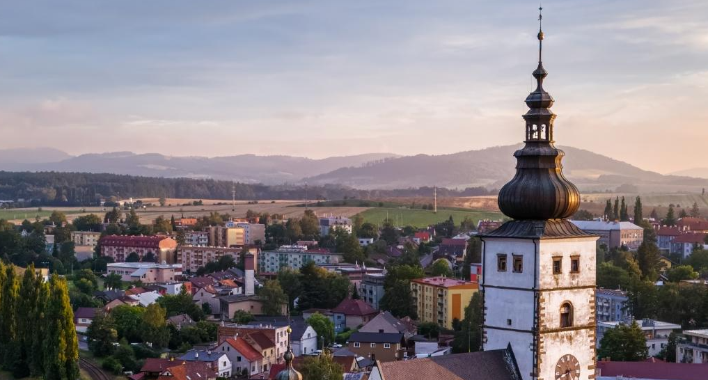 Kirchturm, im Hintergrund eine Stadt und Berge