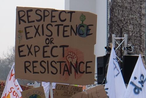 Eine Demonstration mit einem Pappschild mit der Aufschrift "Respect Existence or Expect Resistance"