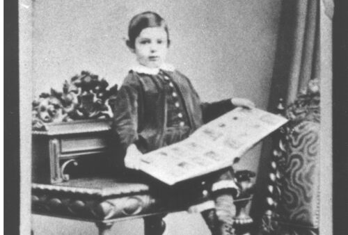 A black-and-white photograph: a boy sitting with a picture book.