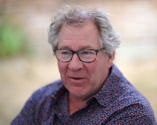 A portrait of Richard Cockett: a man with gray hair, glasses, and a patterned shirt.